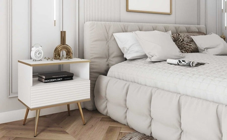 Szafka nocna z szufladą Luxury biała elegancki design korpus zwieńczony złotą listwą szafka z ryflowanym frontem złote wysokie nogi